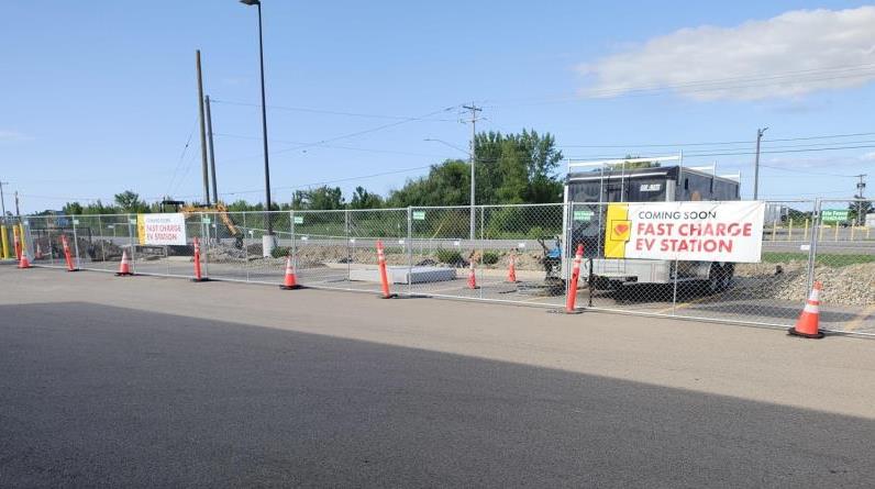 Construction on EV Fast Chargers with a banner that says "Coming Soon Fast Charge EV Station"