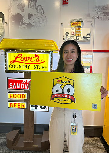 Love's intern, Eugenia, holding a Love's 60th anniversary paper